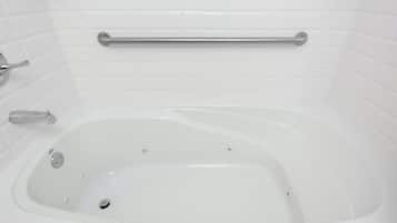Una vasca da bagno bianca con maniglia di sostegno, rubinetteria e scarico.