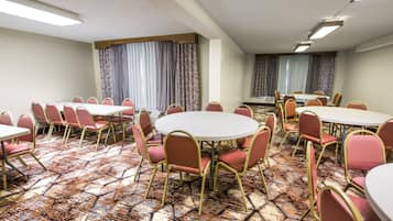 A conference room with round tables and chairs, patterned carpet, and curtains.