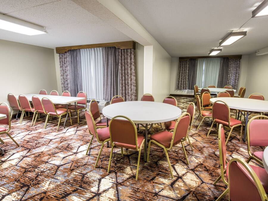 A conference room with round tables and chairs, patterned carpet, and curtains.