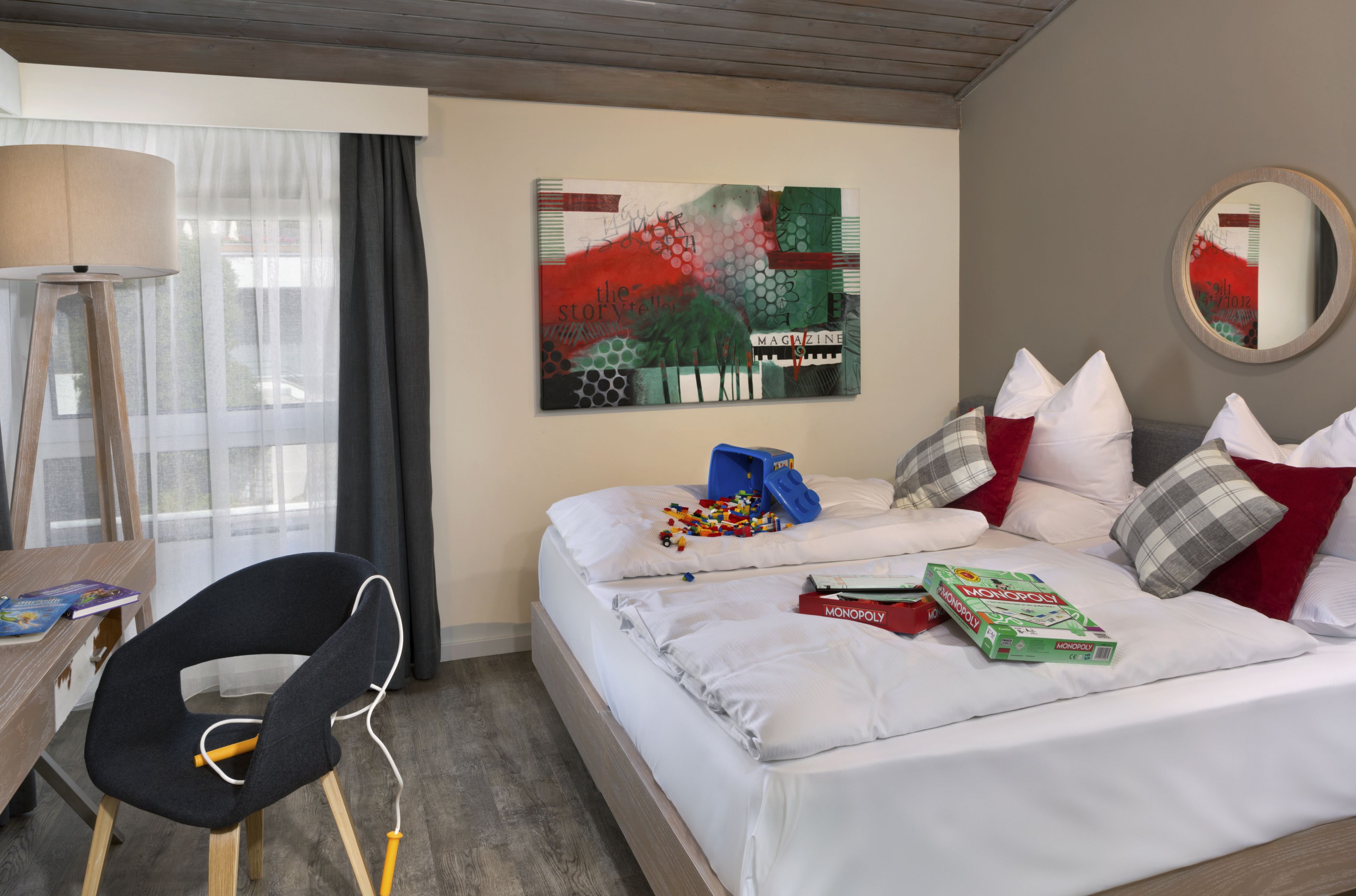 Une chambre d’hôtel comprenant un lit, des oreillers, un bureau avec une chaise, une lampe et une œuvre d’art murale.