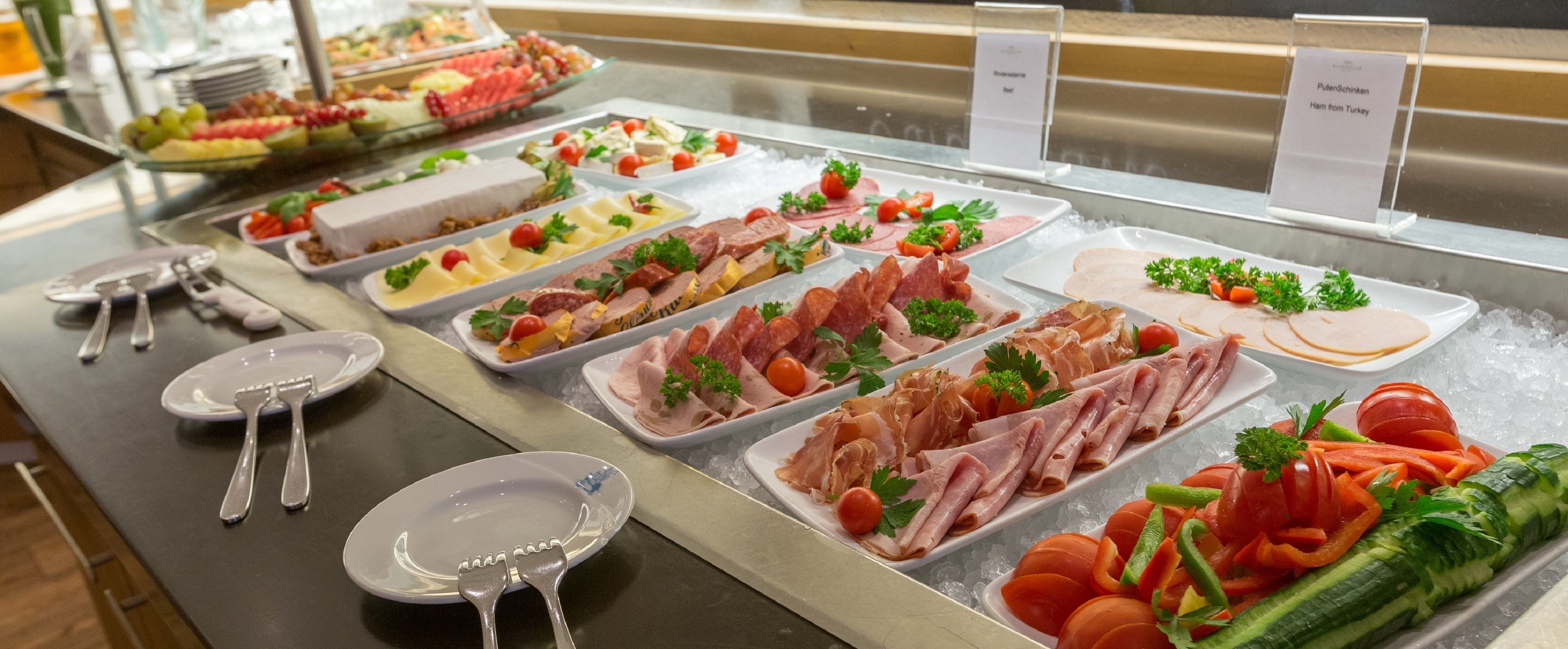 A buffet with various food options including meats, cheeses, and vegetables.