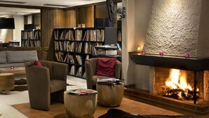 A cozy living room with a fireplace, a bookshelf, and comfortable seating. - Karma Bavaria (Schliersee)