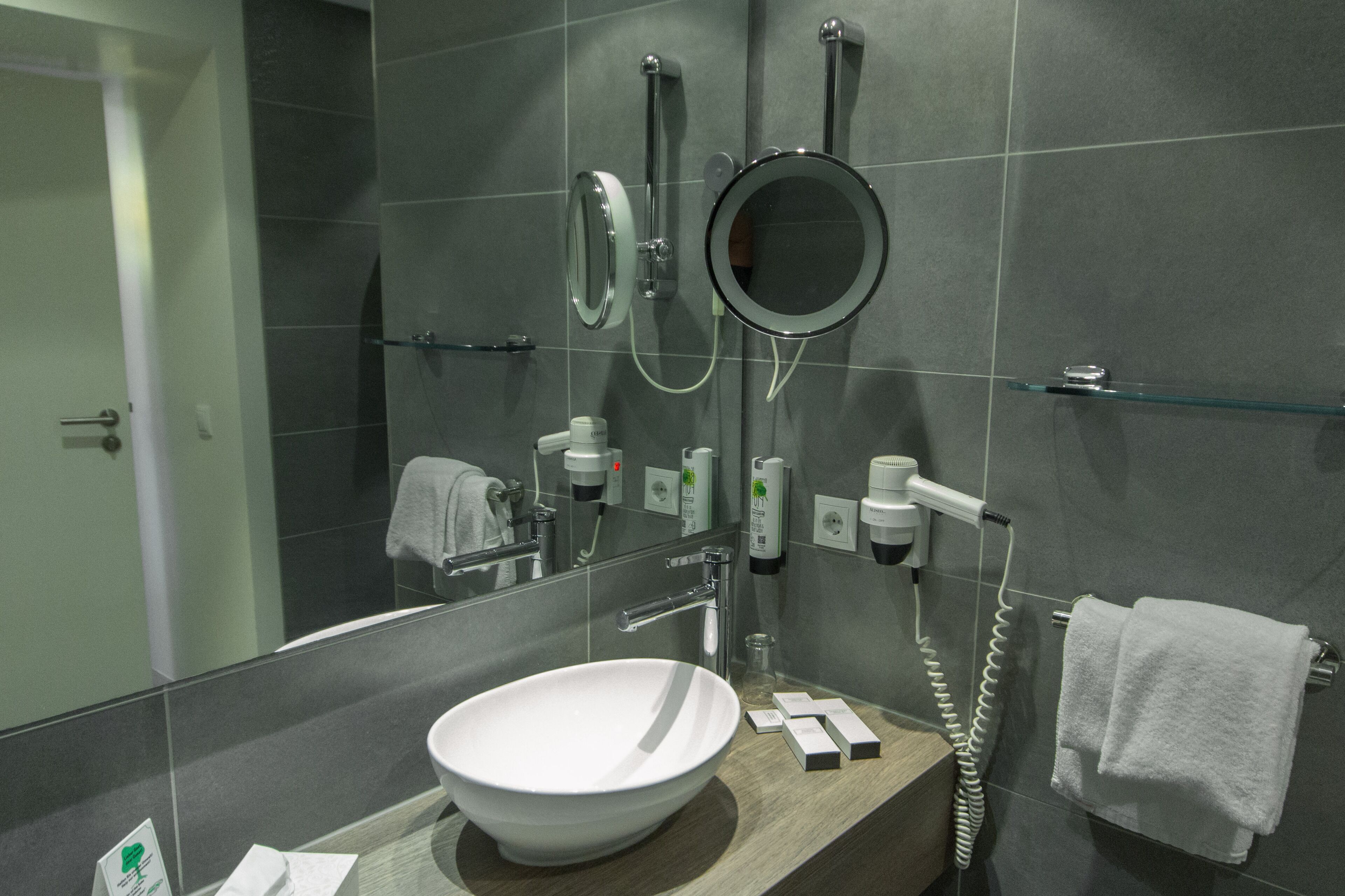 Un baño moderno con un espejo grande, un lavabo y un perchero para toallas.