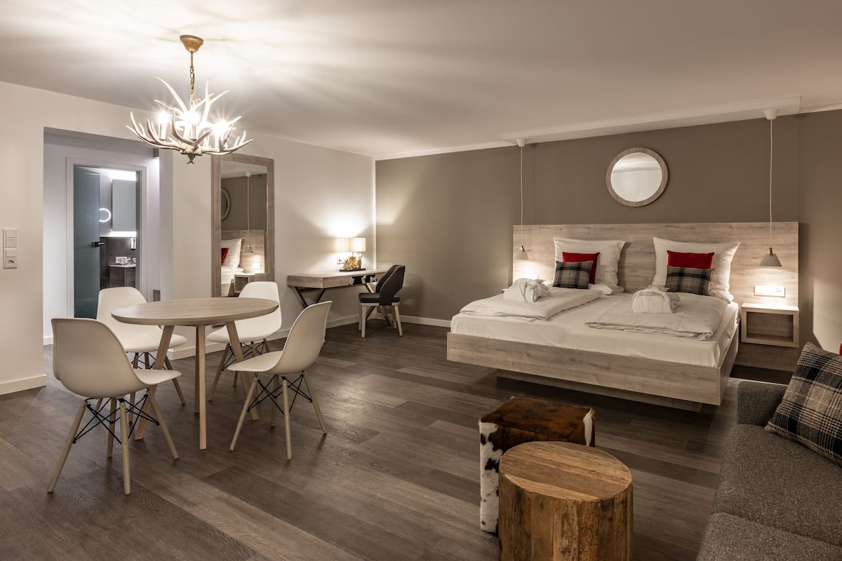 Quarto de hotel moderno com uma cama grande, uma escrivaninha, uma mesa de jantar e um lustre.