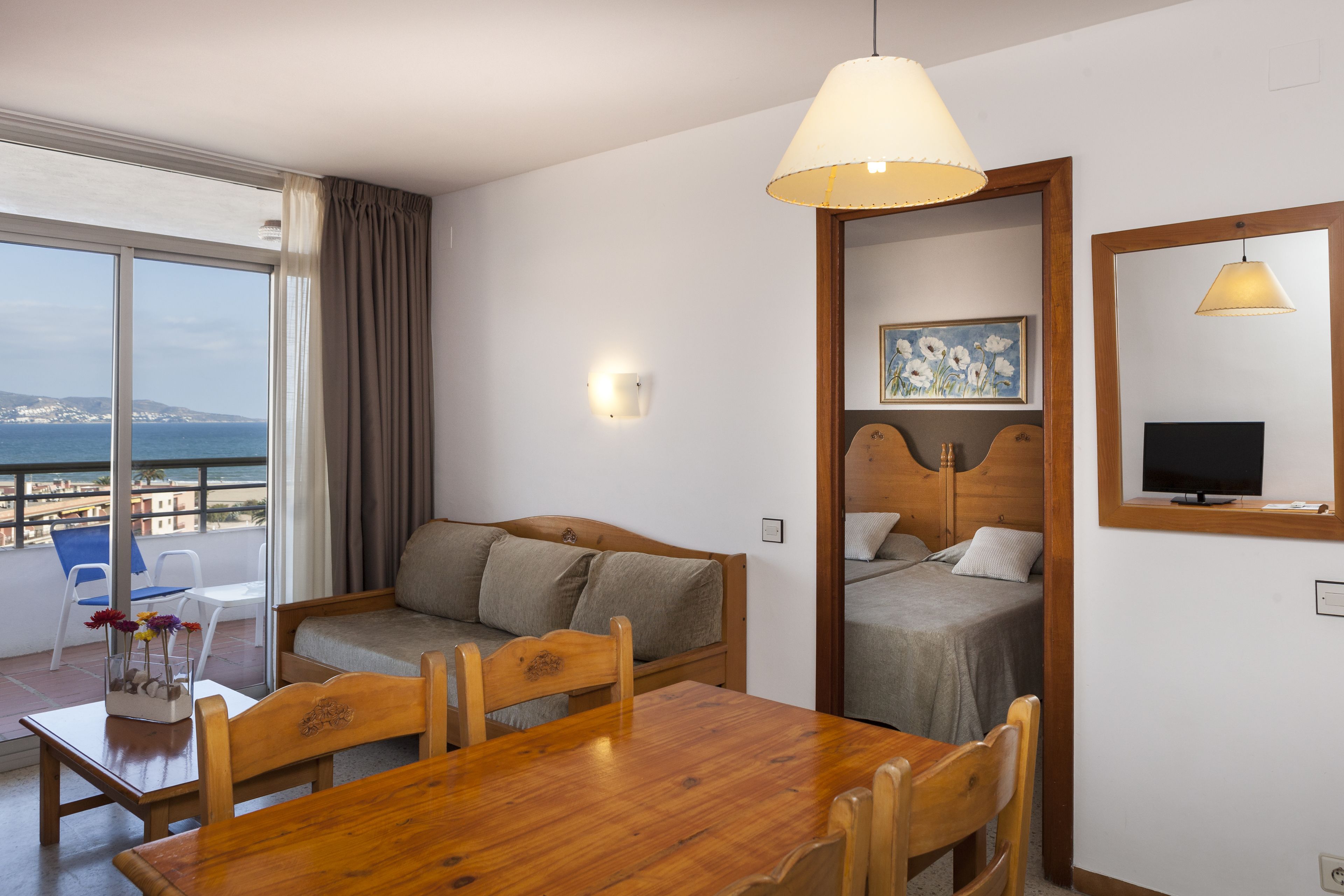 Una habitación de hotel con balcón, una mesa de comedor de madera, un sofá y una cama.