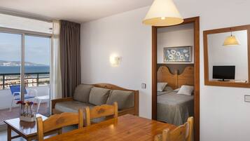 Una habitación de hotel con balcón, una mesa de comedor de madera, un sofá y una cama.