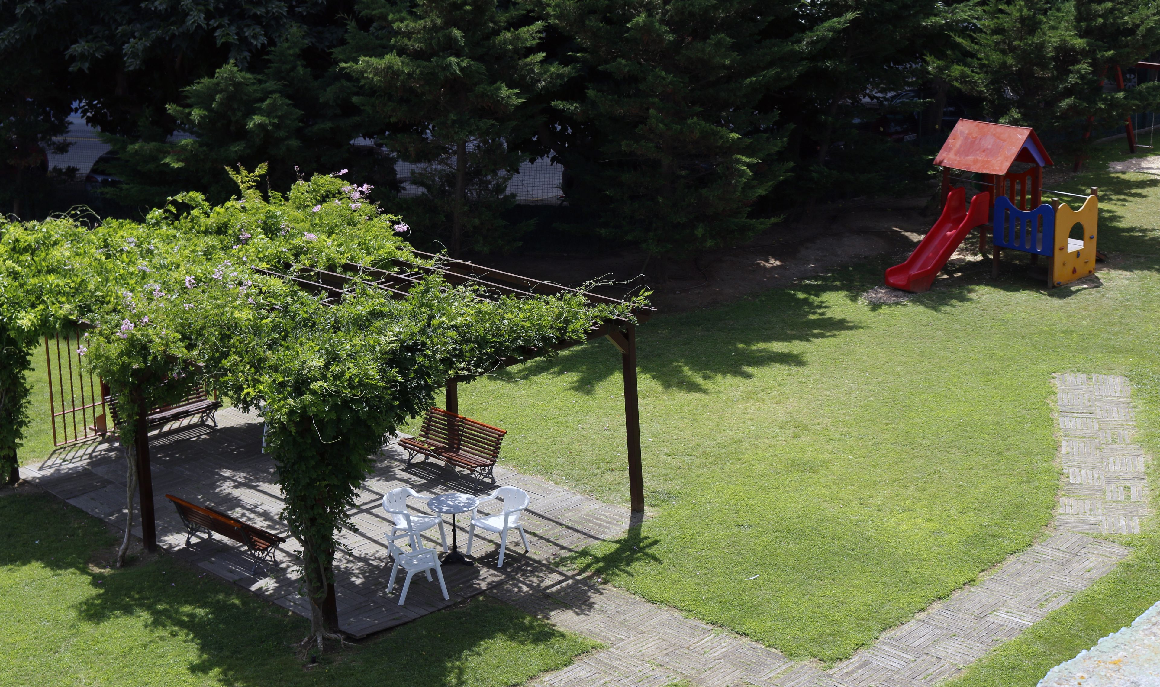 A patio with a pergola, outdoor seating, and a playground with slides.