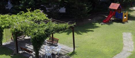 A patio with a pergola, outdoor seating, and a playground with slides.
