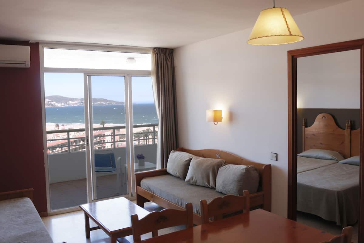 Een hotelkamer met balkon, een bank, een bed en een tafel.