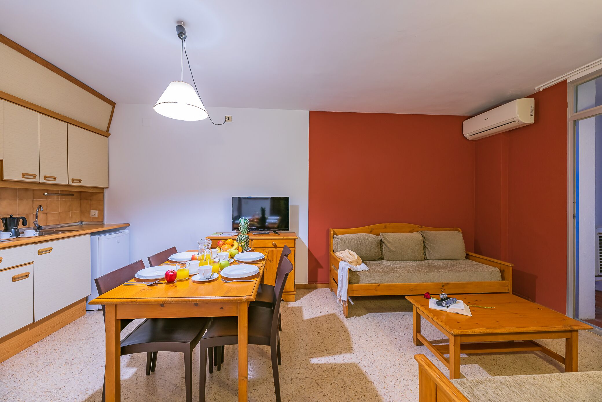 A compact living space with a dining area, kitchenette, and a sofa.