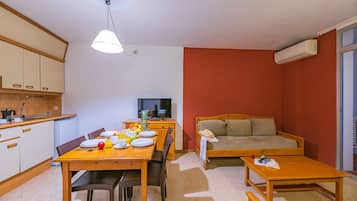 A compact living space with a dining area, kitchenette, and a sofa.