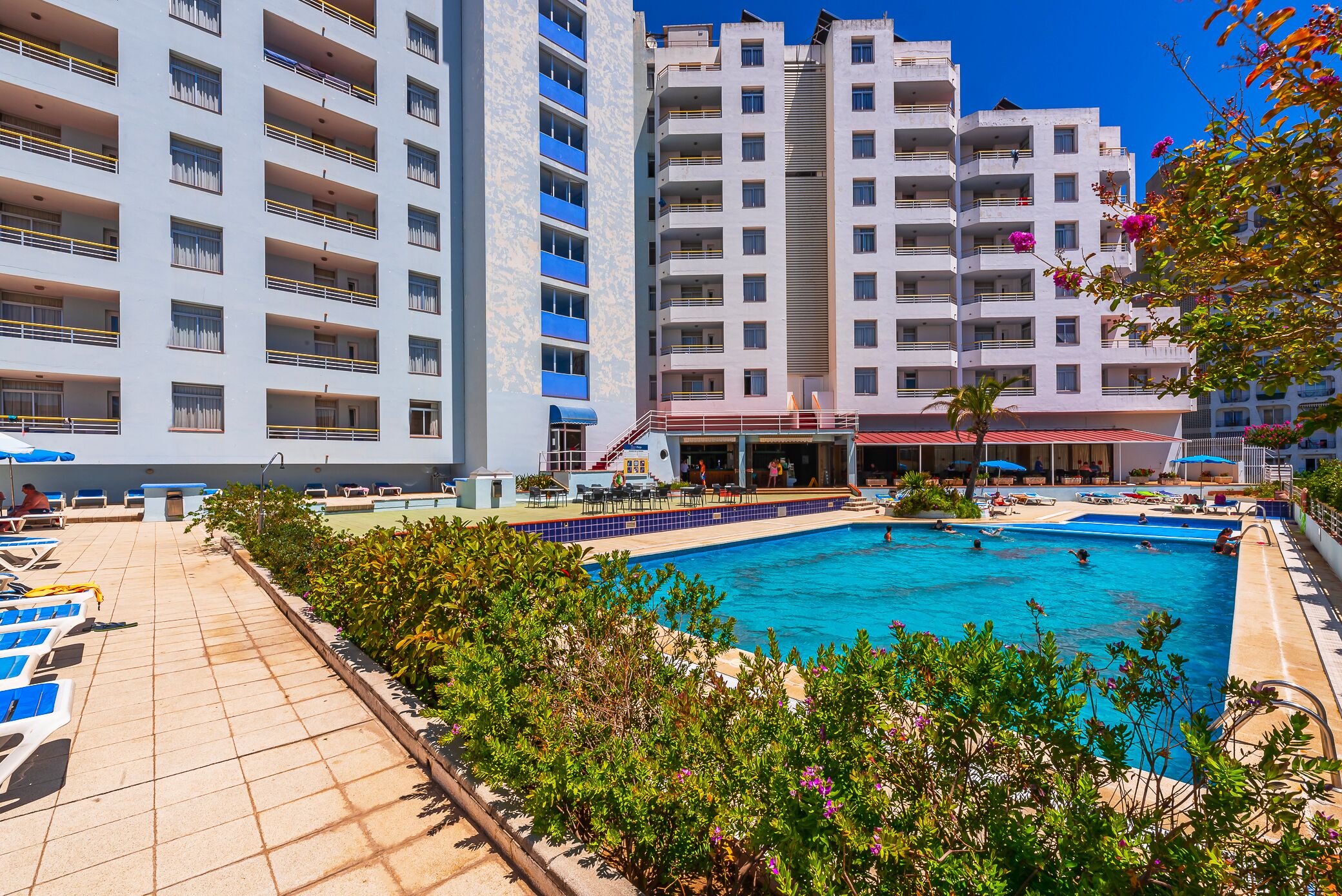 Una piscina al aire libre, sombrillas, tumbonas