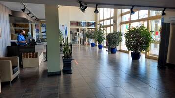 Eine geräumige Lobby mit einer Rezeption, Topfpflanzen und großen Fenstern, die viel Tageslicht hereinlassen.