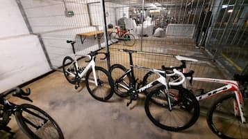 A secure bike storage area with metal fencing, a concrete floor, and several bicycles.