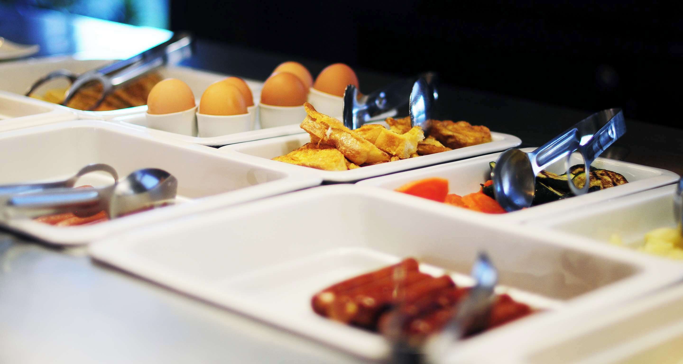 A buffet with various food items including eggs, fried foods, and sauces.