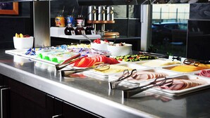A buffet with various food options, including meats, cheeses, and fruits.