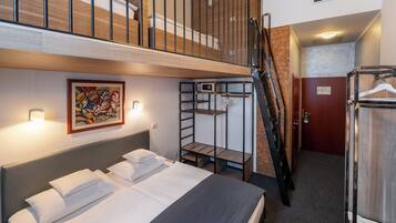 A hotel room with a bunk bed, a painting, a wardrobe, and a staircase.