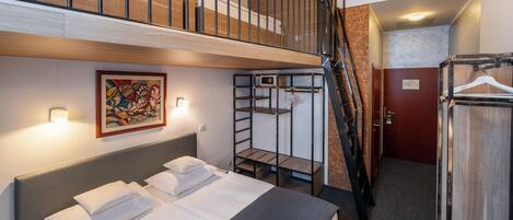 Habitación de hotel con literas, un cuadro, un armario y una escalera.