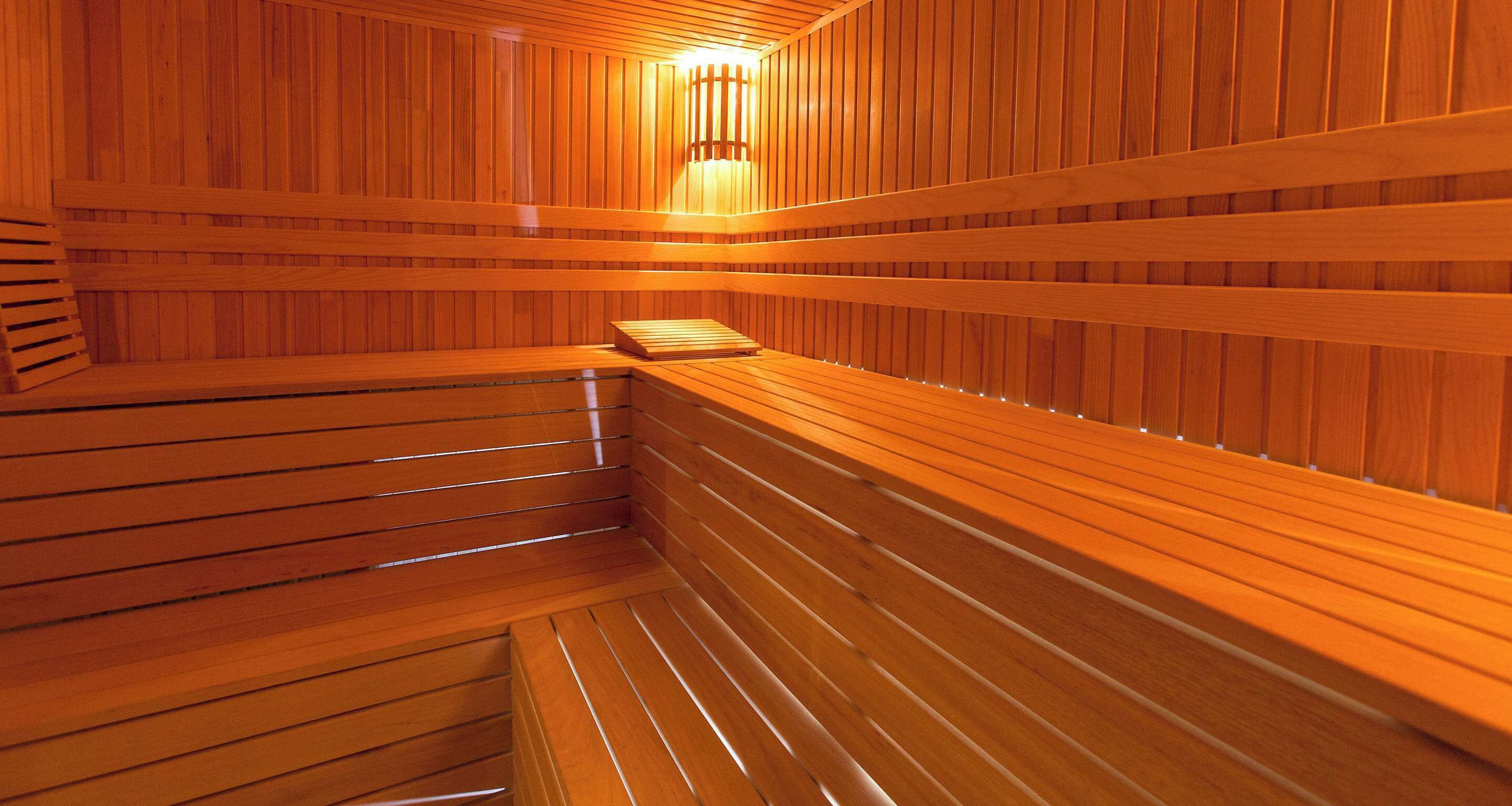 A wooden sauna with benches and a light fixture.