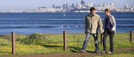A couple walking along a path with a city skyline in the background.