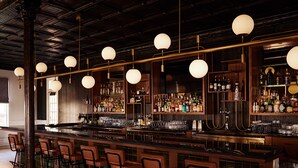 Un bar avec un long comptoir, de nombreux tabourets et des étagères remplies de bouteilles.