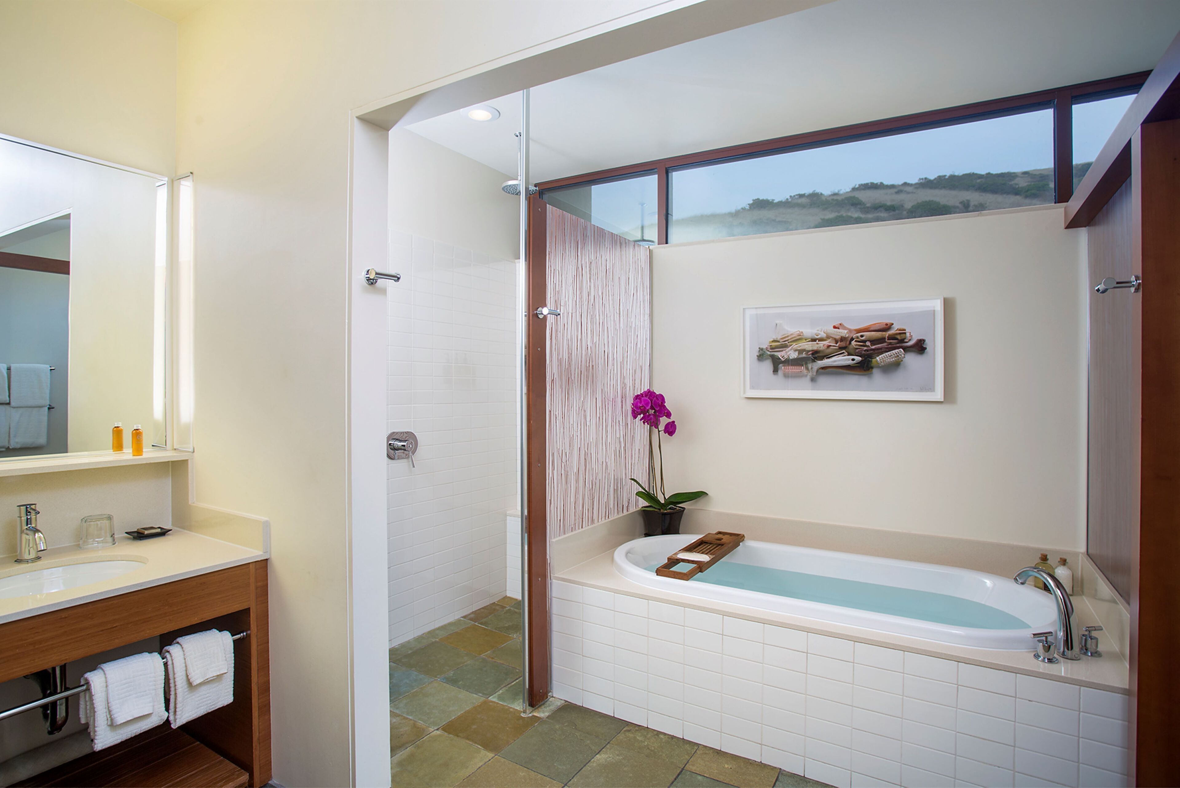 A modern bathroom with a large bathtub, a shower area, and a vanity with a mirror.