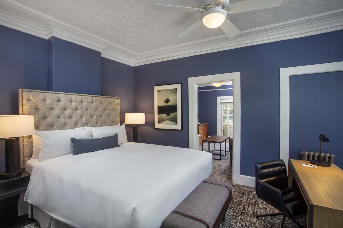 A hotel room with a large bed, two bedside tables, a desk, and a chair.