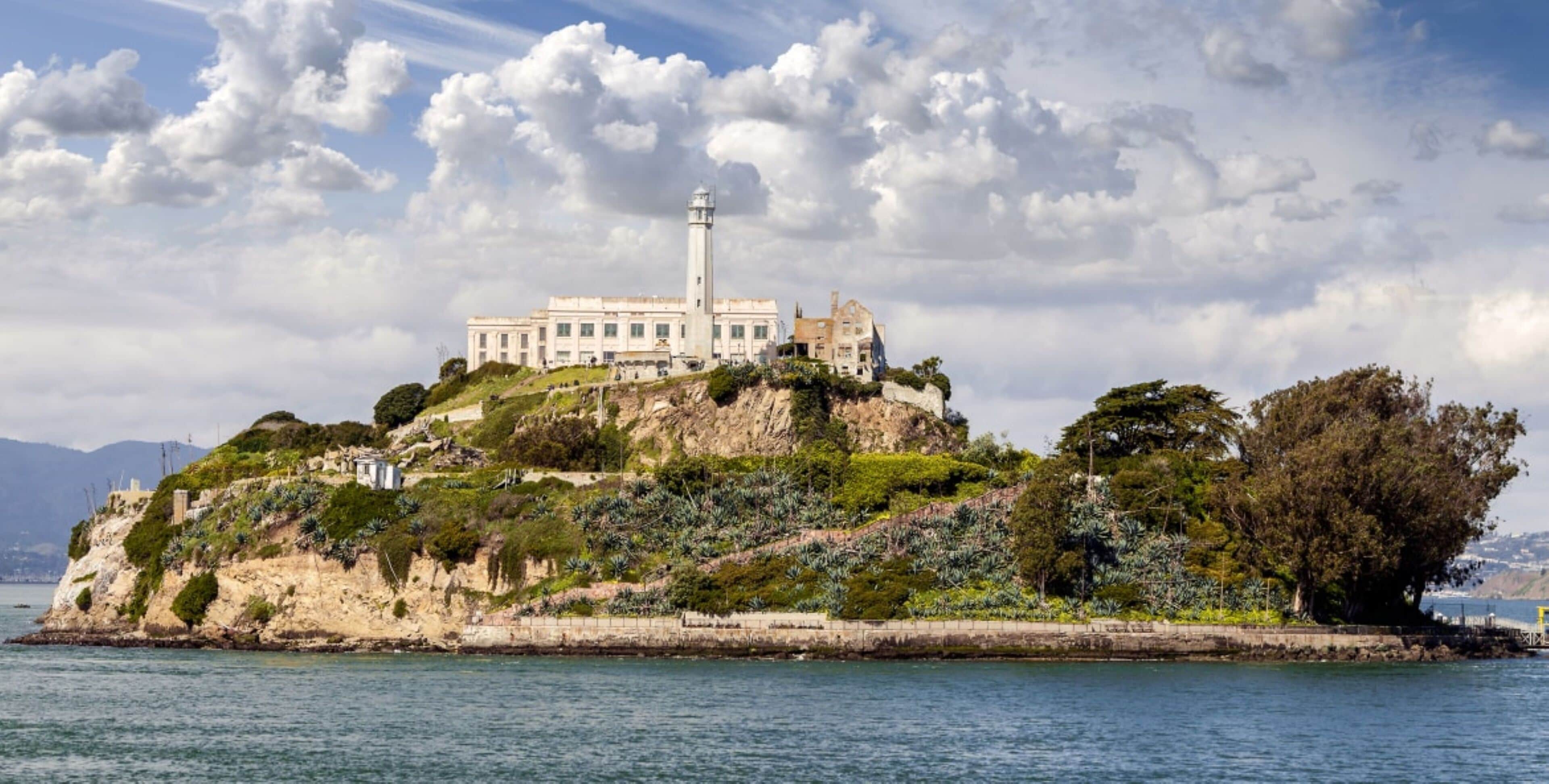 A coastal building with a lighthouse on a hill, surrounded by greenery and overlooking the sea.