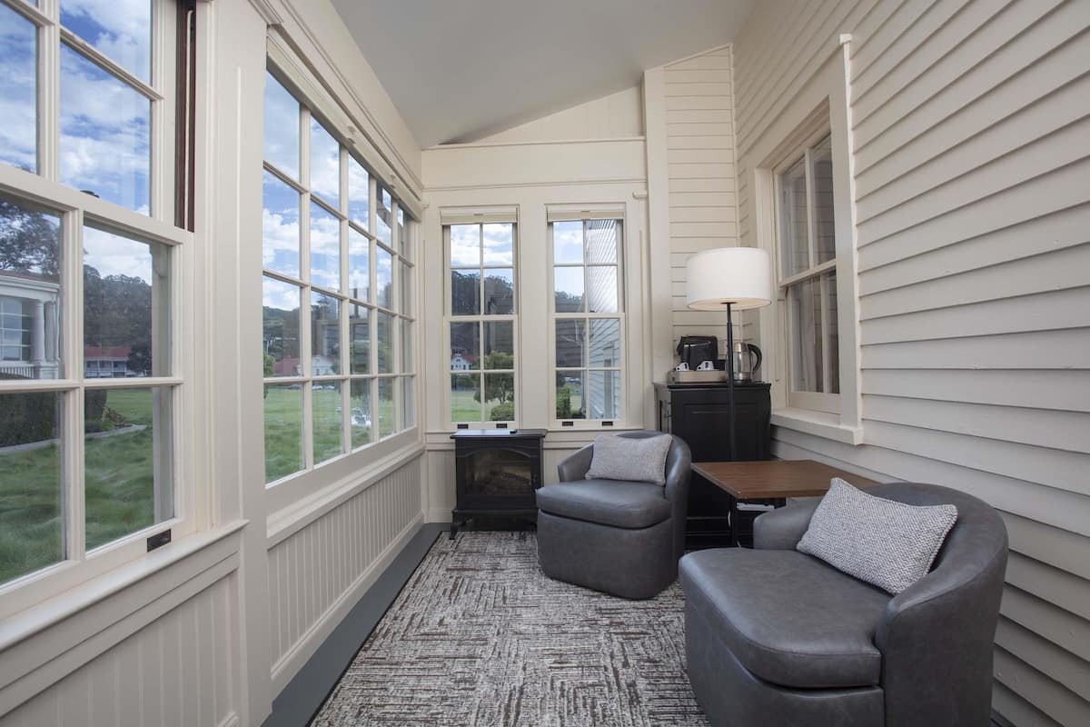 A room with large windows, a fireplace, a sofa, and a lamp.