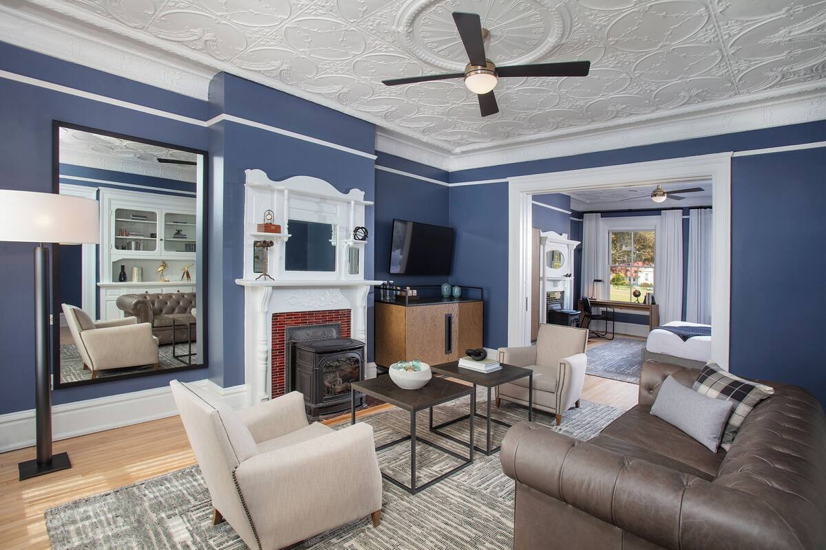 A living room with a fireplace, sofa, armchairs, and a television.