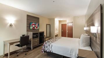 A hotel room with a bed, a desk, a television, a wardrobe, and a bathroom.