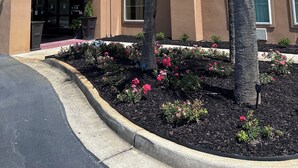 A Red Roof Inn with a red roof, beige walls, and a landscaped garden with pink flowers and palm trees. - Red Roof Inn Panama City (Panama City)