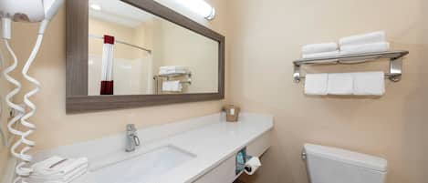 A bathroom with a white sink, a mirror, a toilet, and a towel rack.