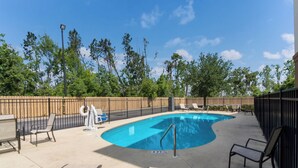 A swimming pool with a curved edge, surrounded by a fence, and equipped with lounge chairs and a water slide. - Red Roof Inn Panama City (Panama City)