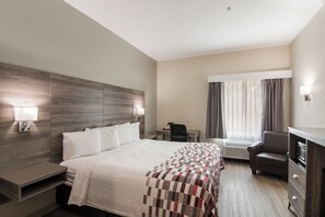 A hotel room with a large bed, a desk, a chair, and a TV. - Red Roof Inn Panama City (Panama City)