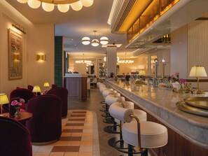 A bar area with multiple seating options, including bar stools and cushioned chairs, with a counter and bar equipment. - Hotel Condal (Barcelona)