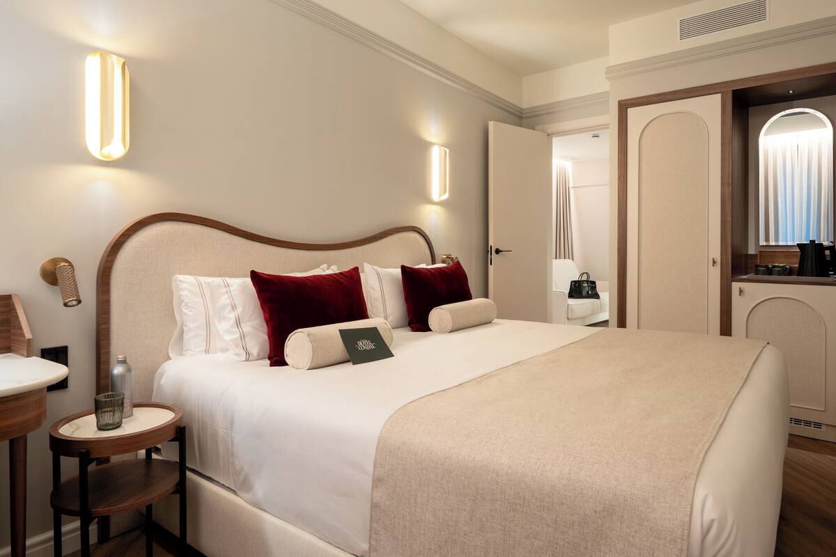 A hotel room with a bed, bedside table, lamp, and a mirror.