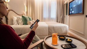Ein Hotelzimmer mit Bett, Fernseher, einem Glas Orangensaft und einer Ablage mit Snackschalen.