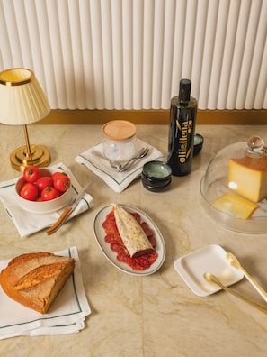 A dining table with a variety of food items, a lamp, and a bottle of olive oil. - Hotel Condal (Barcelona)