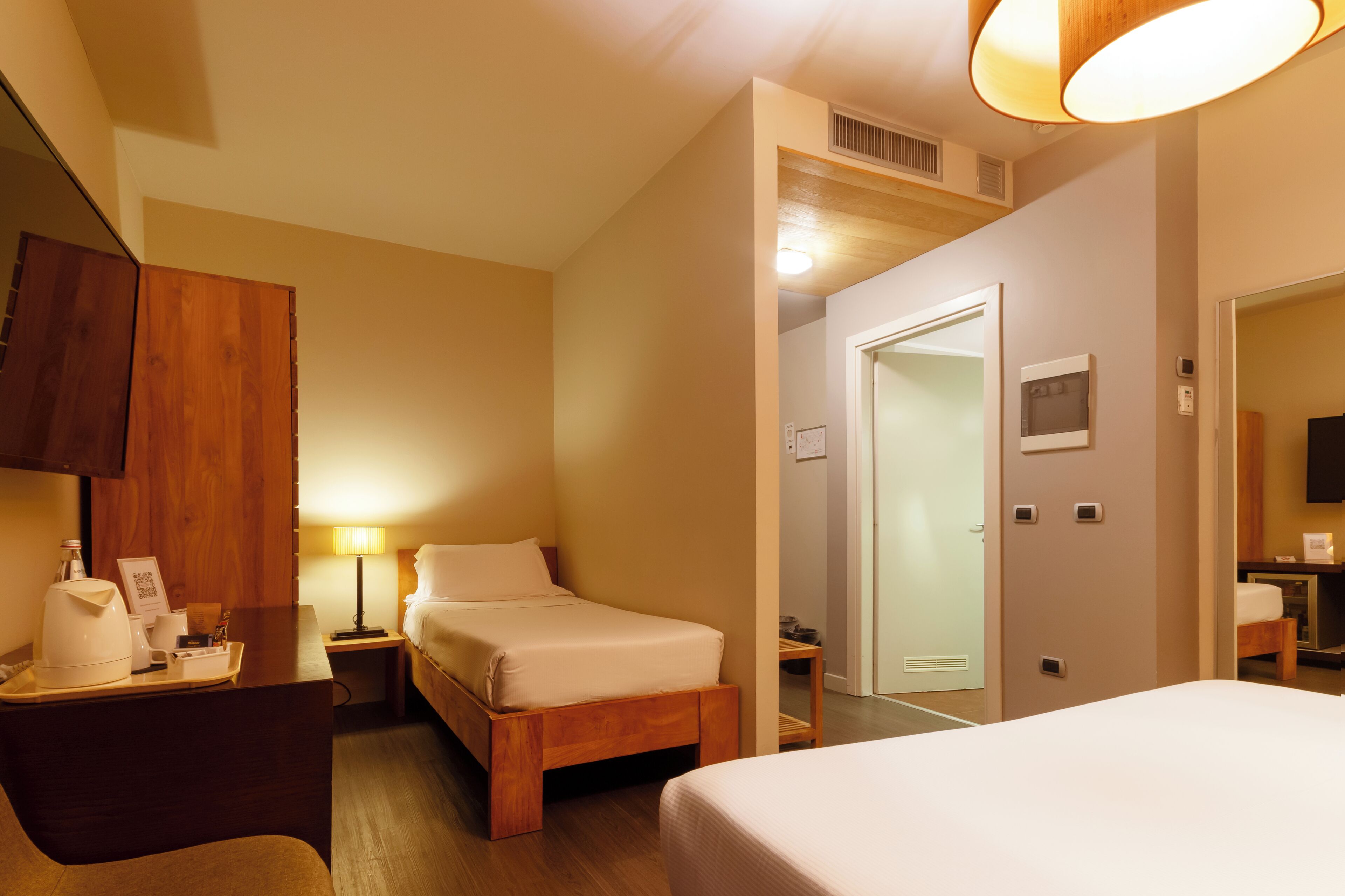 Une chambre d’hôtel comprenant un lit, une table de chevet, une lampe et une armoire en bois.