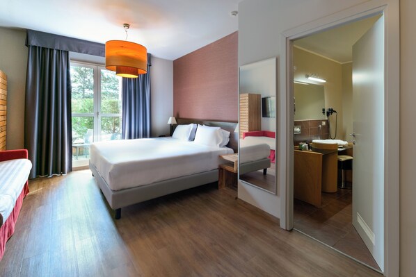 A modern hotel room with a large bed, bedside tables, a mirror, and a view of the outdoors. - Admiral Park Hotel by Falco D'Oro Hotels (Zola Predosa)