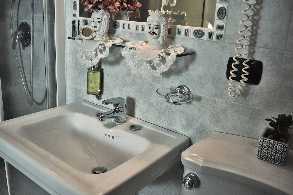 Un baño con un lavamanos grande, un espejo y un inodoro pequeño.
