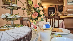 Montaje de bufé con diversos alimentos, incluyendo un pastel y productos de repostería, dispuestos sobre una mesa.