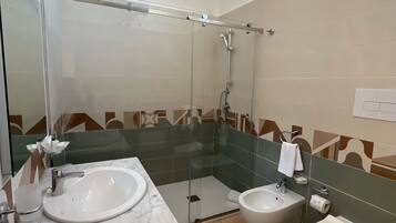Ein modernes Badezimmer mit einer Duschkabine, zwei Waschbecken, einer Toilette und einem Spiegel.