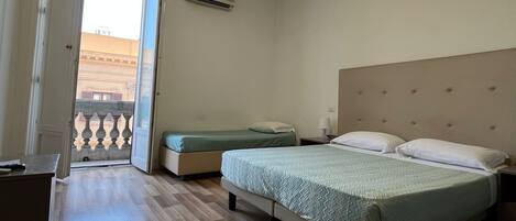 A hotel room with a bed, a desk, and a view of the outside.