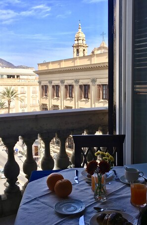 A balcony with a table set for breakfast, overlooking a historic building with domes and a cross on top. - 38 Aira Hotels (Palermo)