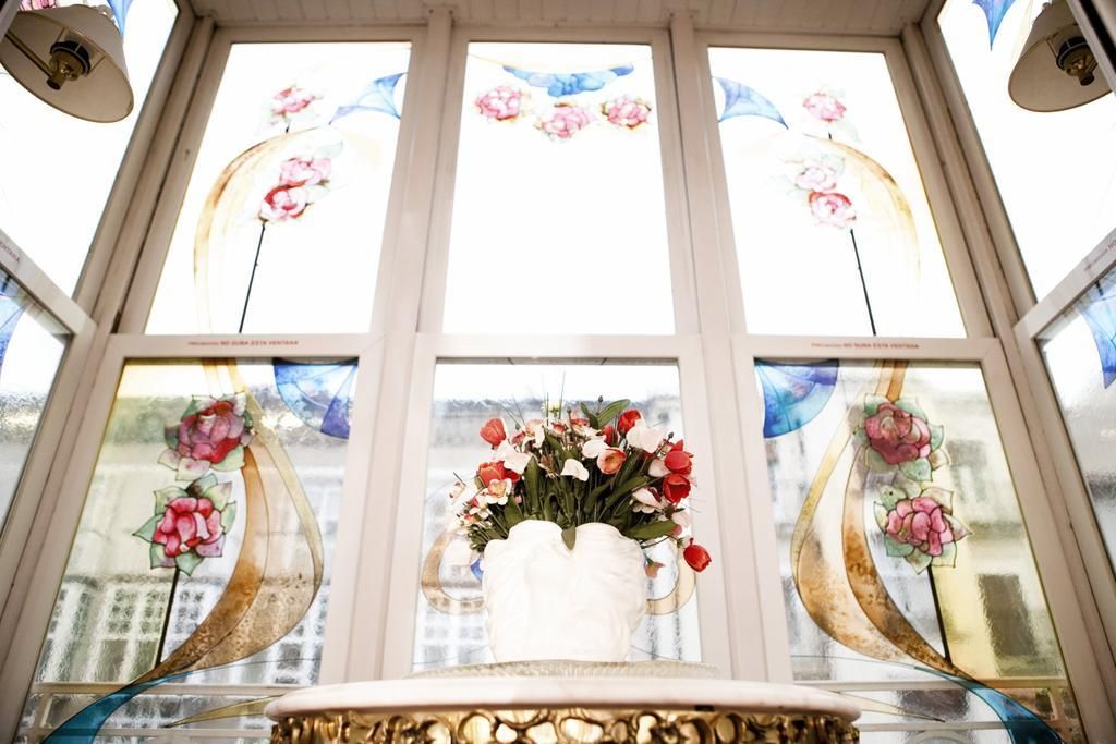 Una habitación con un amplio ventanal decorado con vidrio emplomado floral.