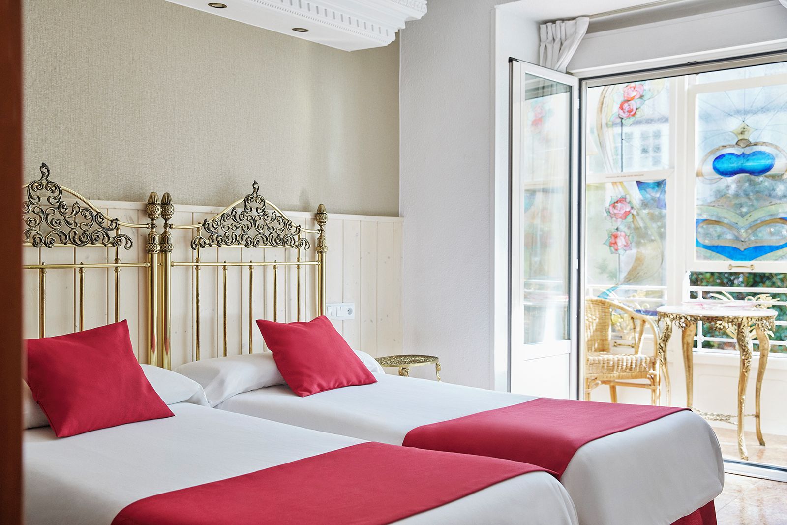 A hotel room with two beds, a balcony, and a view of a building with a blue dome.