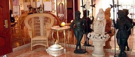 Un vestíbulo con una fuente central, una silla estampada y una estatua de un hombre sosteniendo una espada.