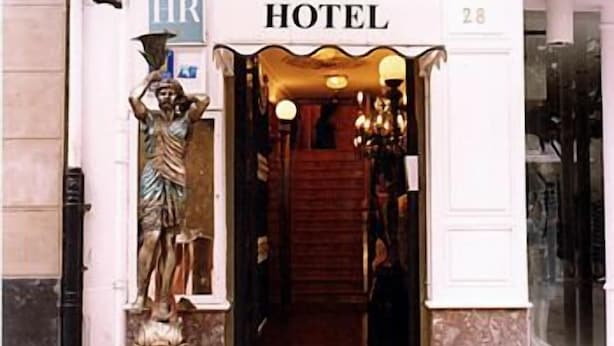 Entrada de un hotel con una estatua de un hombre, un letrero que dice “HOTEL” y el número “28” sobre la puerta.
